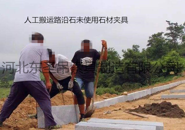 未使用雙人抬石頭的夾子作業(yè)現(xiàn)場，兩人使用鋼絲繩費(fèi)力搬運(yùn)路沿石--河北東圣吊索具制造有限公司--石材夾具|小型攪拌機(jī)|液壓堆高車|手動叉車